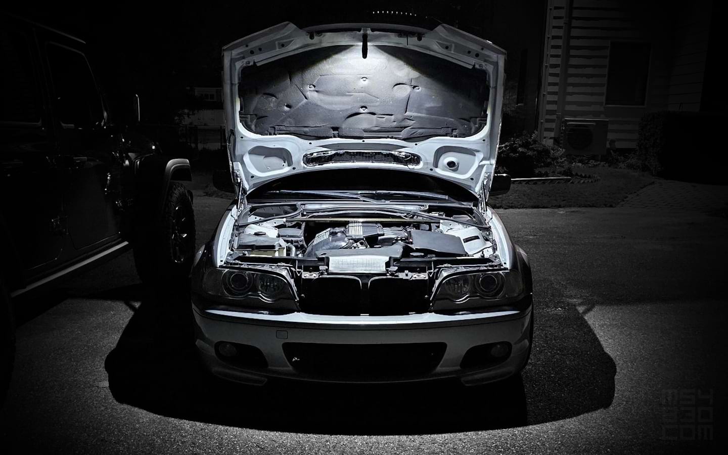 The E46 at night with the freshly serviced engine illuminated from above by a single spotlight.