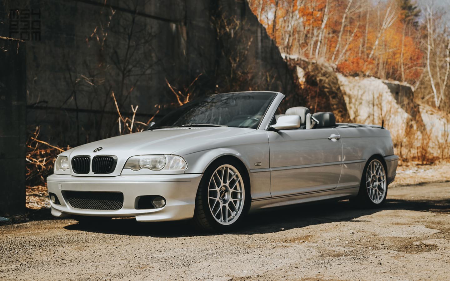 The front of my silver 2002 E46 330Ci parked along a gravel road with the top down.