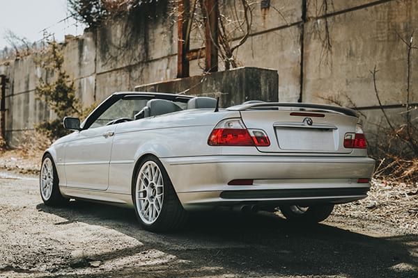 The rear and driver side of my E46 parked along a gravel road with the top down.