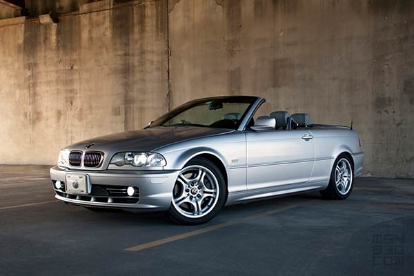 The E46 parked under and overpass with its curves accentuated by evening light.
