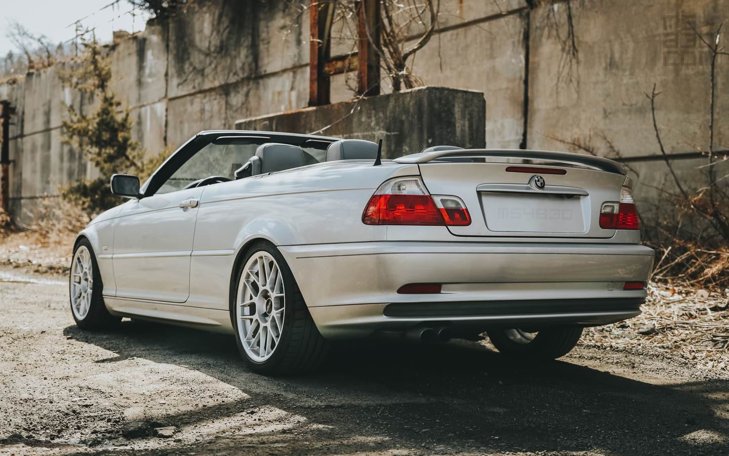 The rear and driver side of my E46 parked along a gravel road with the top down ready to depart.